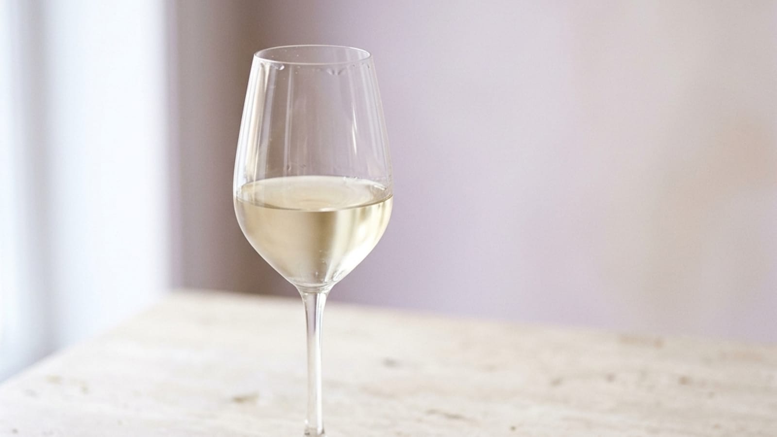 A glass of dealcoholized white wine on a pale table